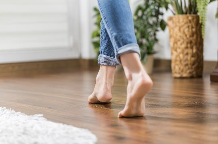 Image of woman’s smooth clean feet walking on hardwood floor