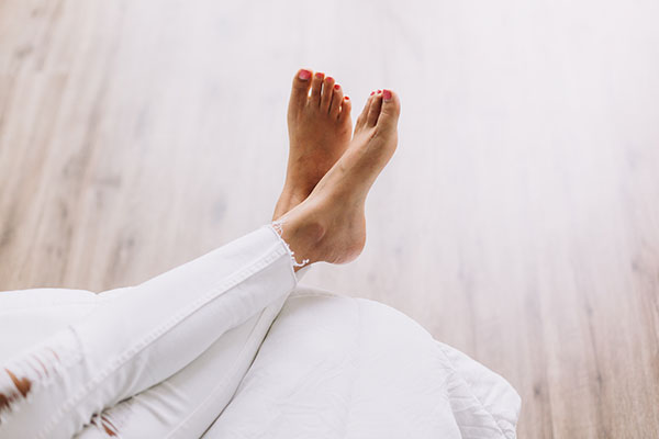 Image of woman’'s pedicured feet on white cushion